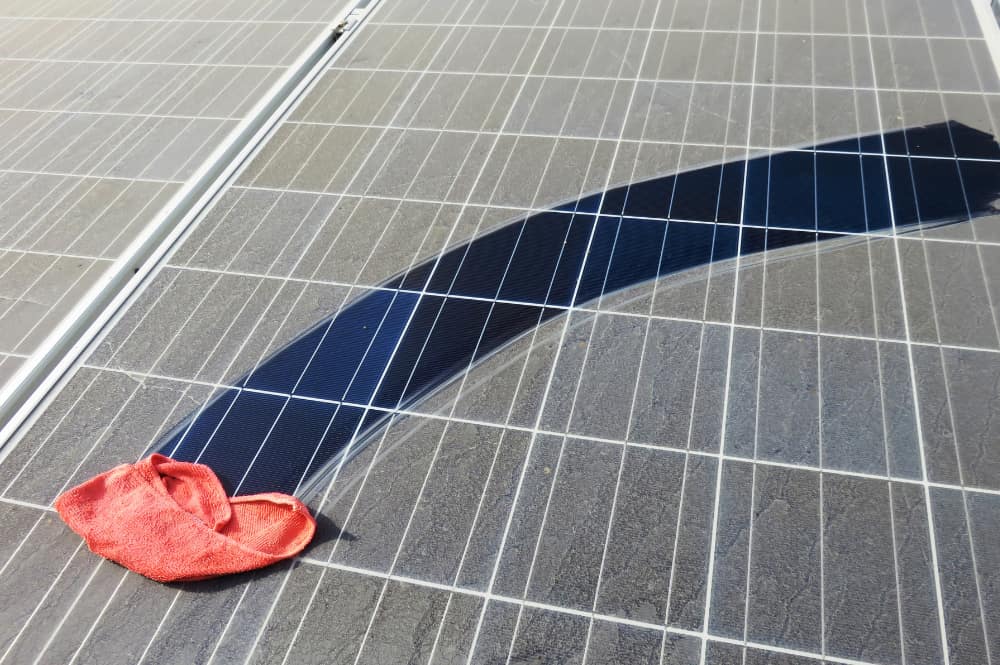 Panneaux solaires en train d'être nettoyés à l'aide d'un chiffon humide