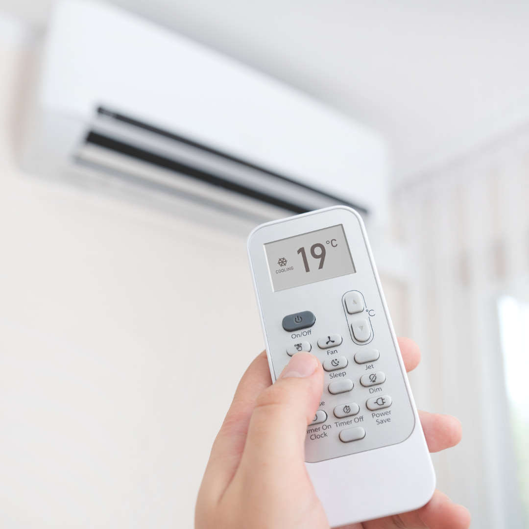 Main qui tient un thermomètre pour régler la température du climatiseur